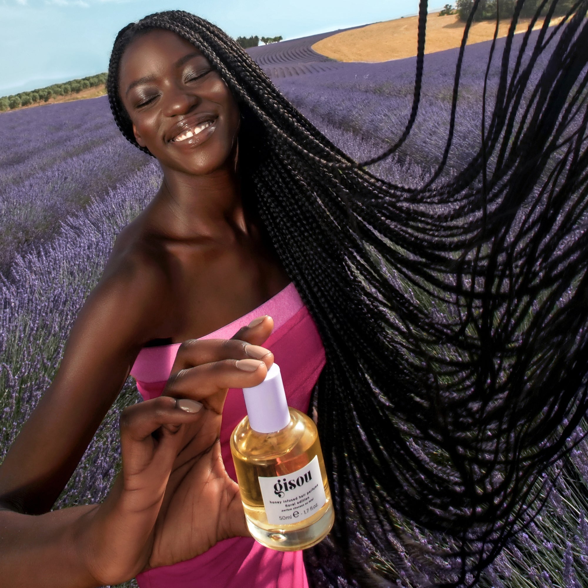 Model holding the hair perfume bottle in a lavender field. 