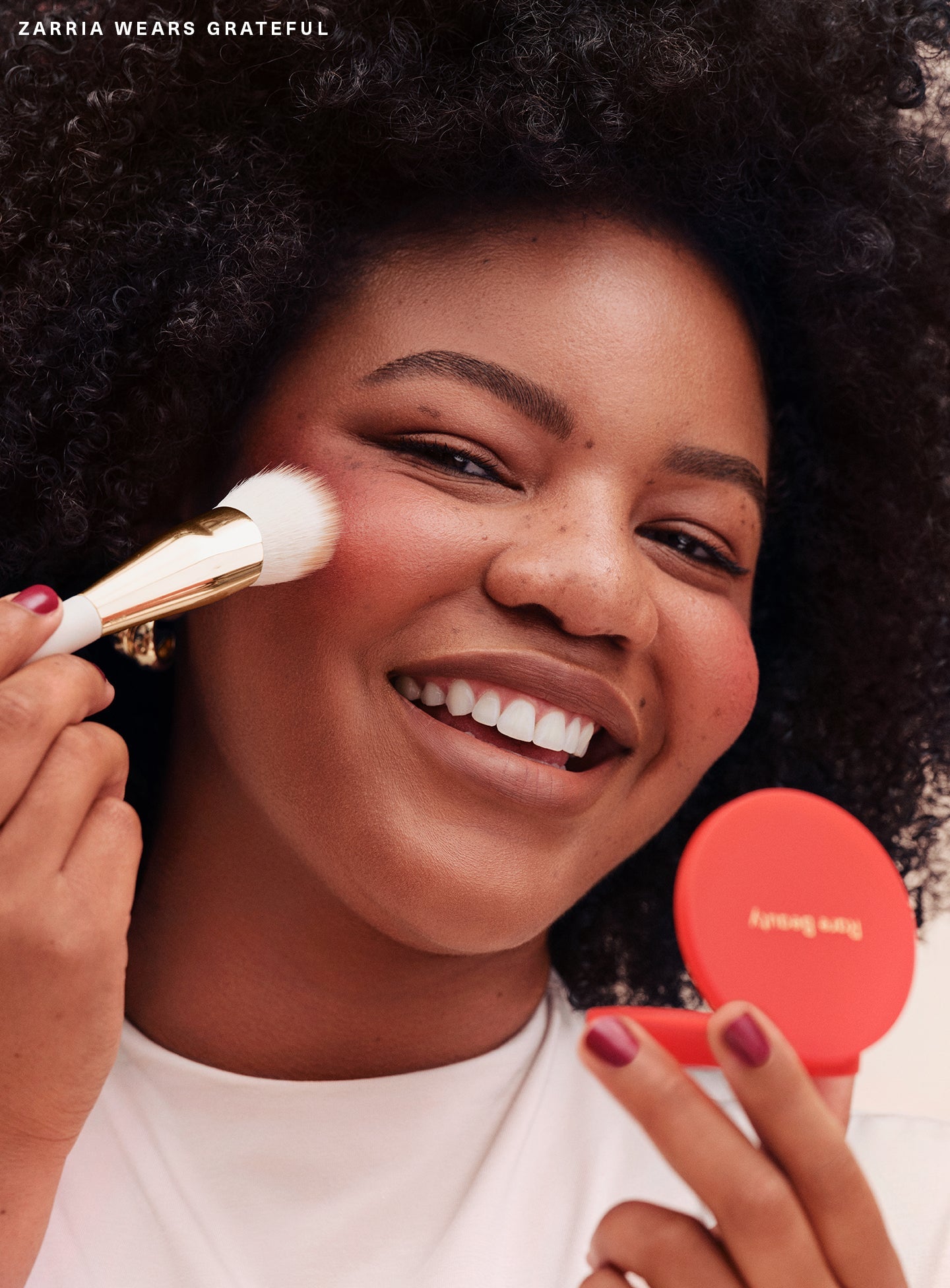 Grateful| Model Zarria wearing Rare Beauty's Soft Pinch Matte Bouncy Blush in the soft red shade Grateful.