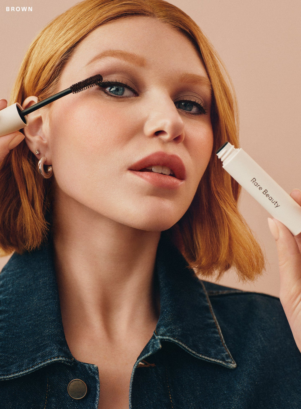 Model with light skin tone modeling Rare Beauty's Perfect Strokes Universal Volumizing Mascara in brown