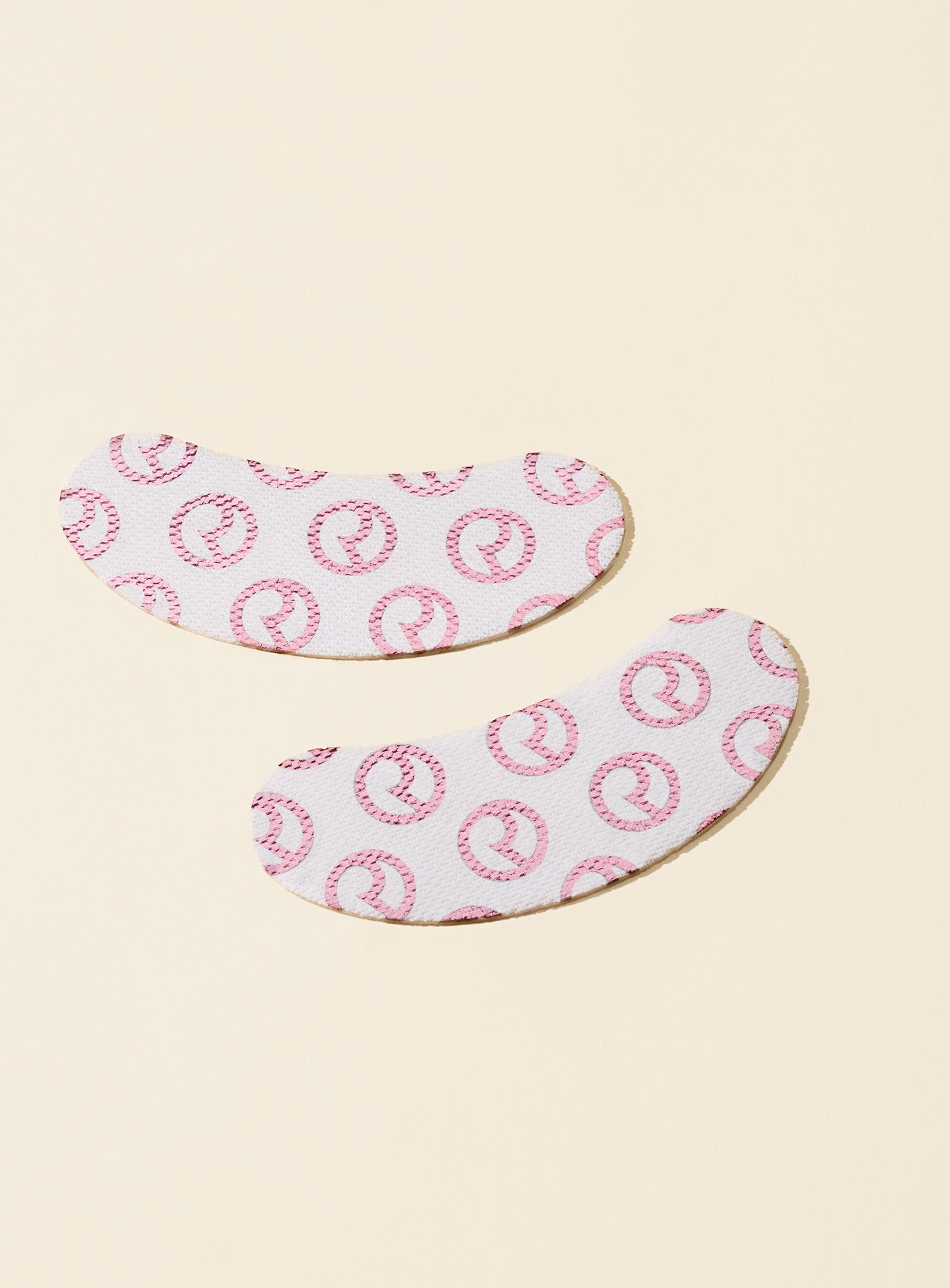 Rare Beauty's Find Comfort Hydrating Under Eye Patches covered with the Rare Beauty logo laying on a soft yellow surface.