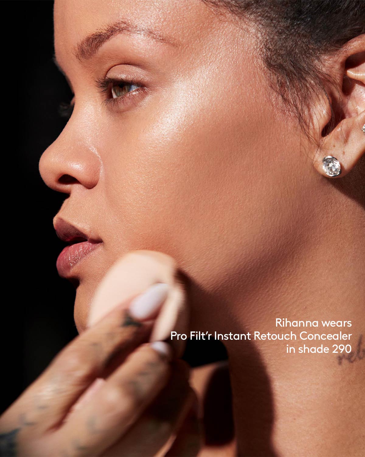 Rihanna applying Fenty Beauty Pro Filt'r Instant Retouch Concealer in shade 290 with makeup sponge. 