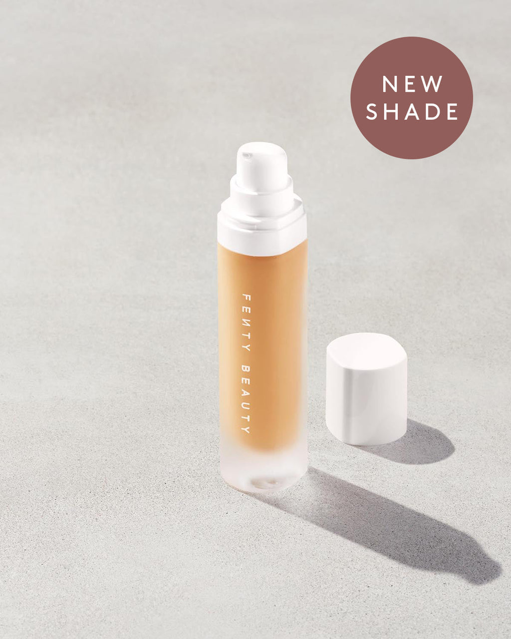 Open bottle of a new shade of Fenty Beauty Pro Filt'r Soft Matte Longwear Foundation with pump dispenser in shade #315 on concrete background