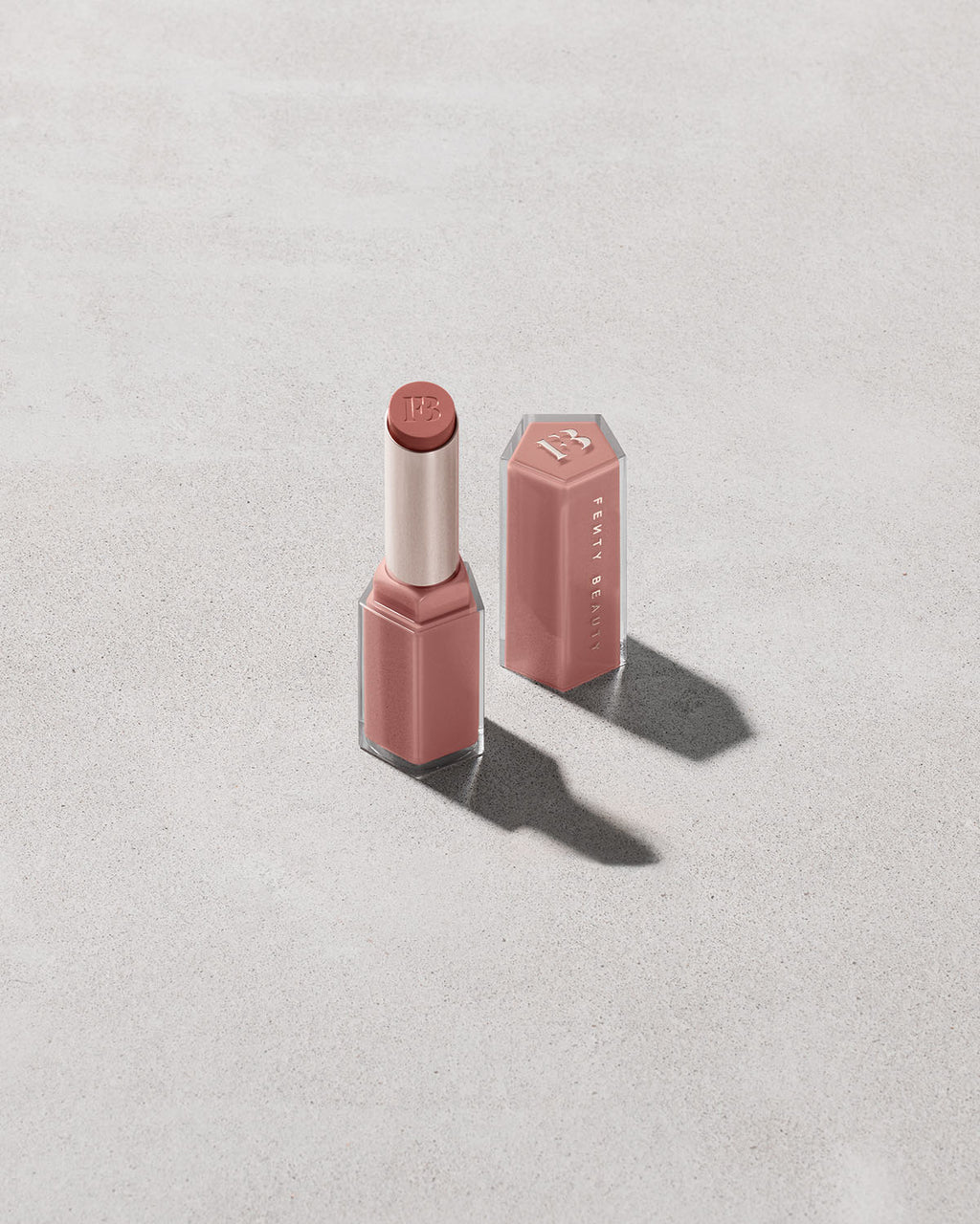 Open product shot of Gloss Bomb Stix in shade Blazed Donut on a concrete background.