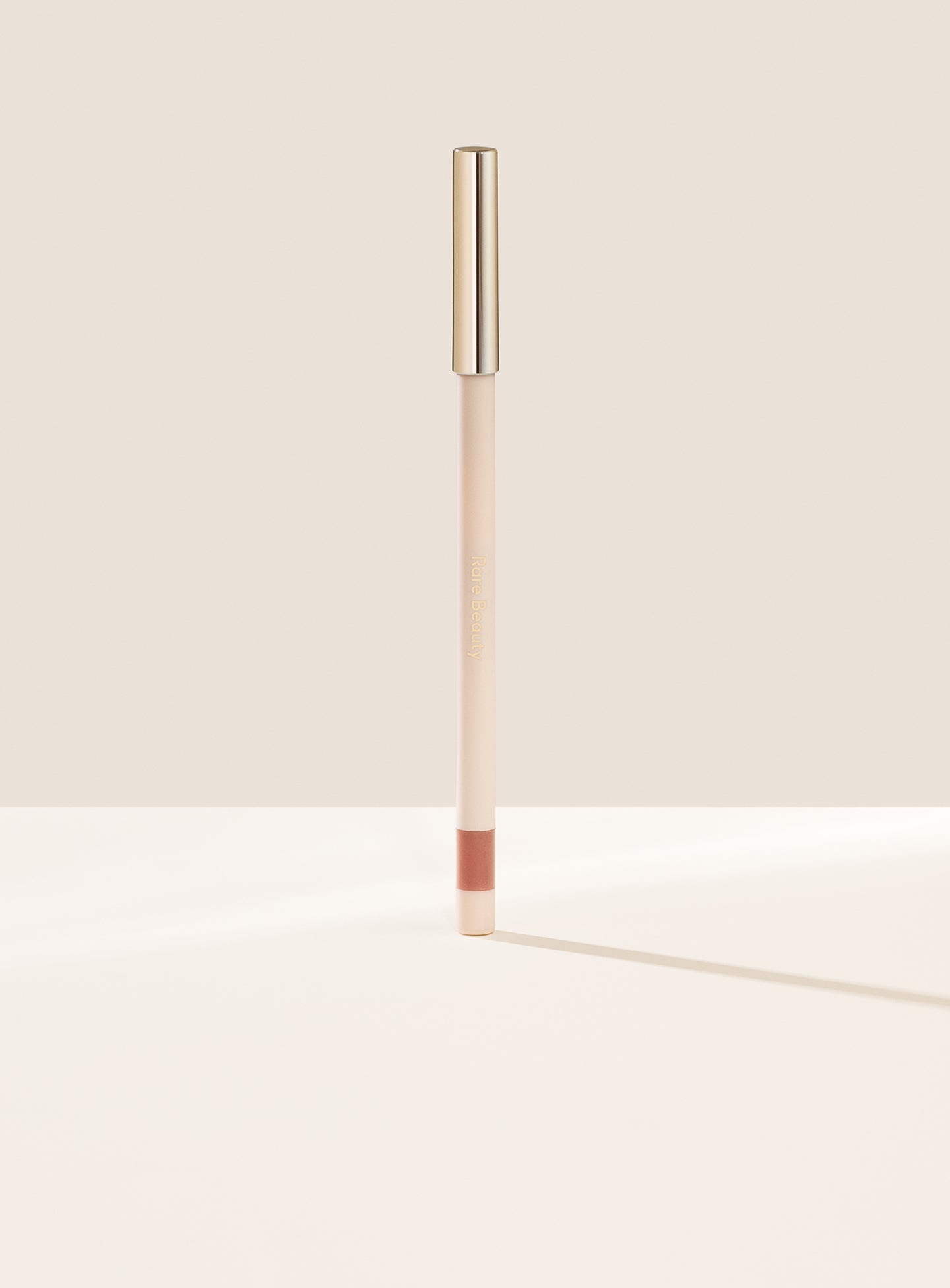 Creative| Rare Beauty's Kind Words Matte Lip Liner, a creamy waterproof lip liner in the shade Creative shown standing up with the cap on. 