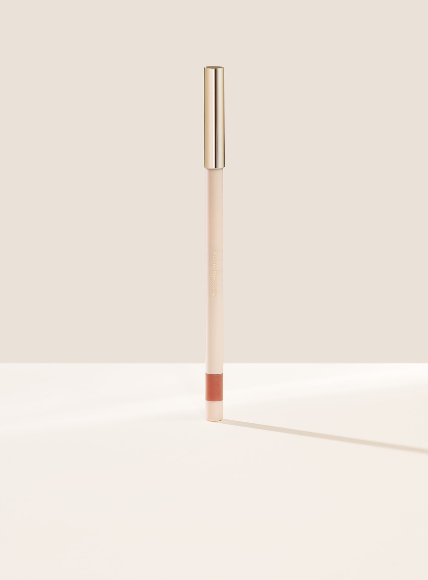 Fun| Rare Beauty's Kind Words Matte Lip Liner, a creamy waterproof lip liner in the shade Fun shown standing up with the cap on.