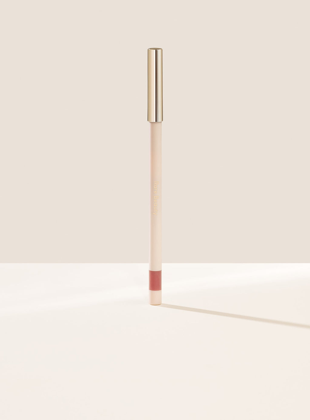 Humble| Rare Beauty's Kind Words Matte Lip Liner, a creamy waterproof lip liner in the shade Humble shown standing up with the cap on.