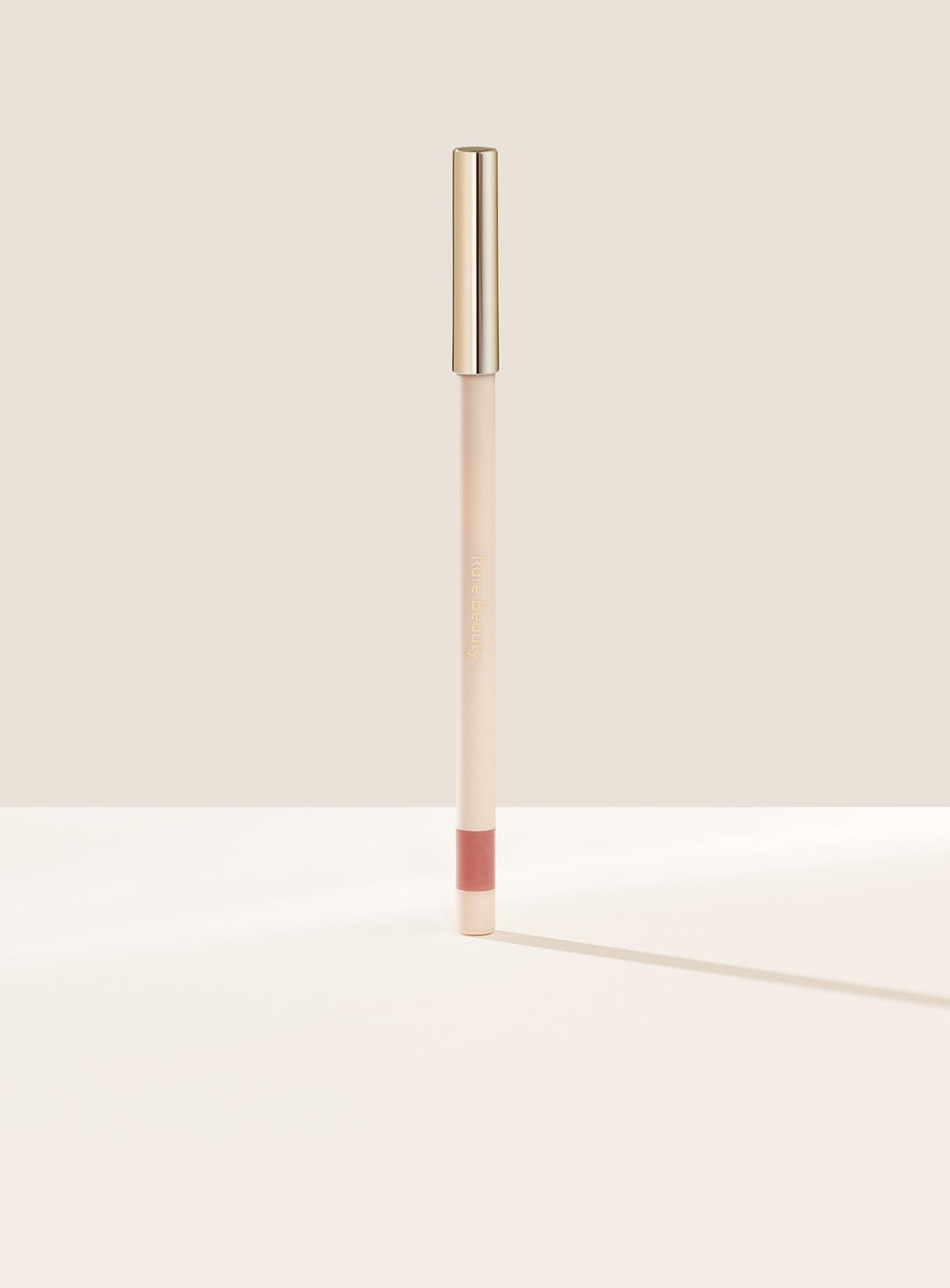 Worthy| Rare Beauty's Kind Words Matte Lip Liner, a creamy waterproof lip liner in the shade Worthy shown standing up with the cap on.