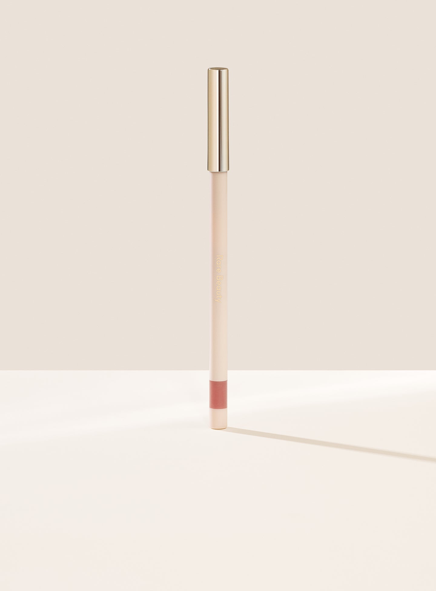 Worthy| Rare Beauty's Kind Words Matte Lip Liner, a creamy waterproof lip liner in the shade Worthy shown standing up with the cap on.